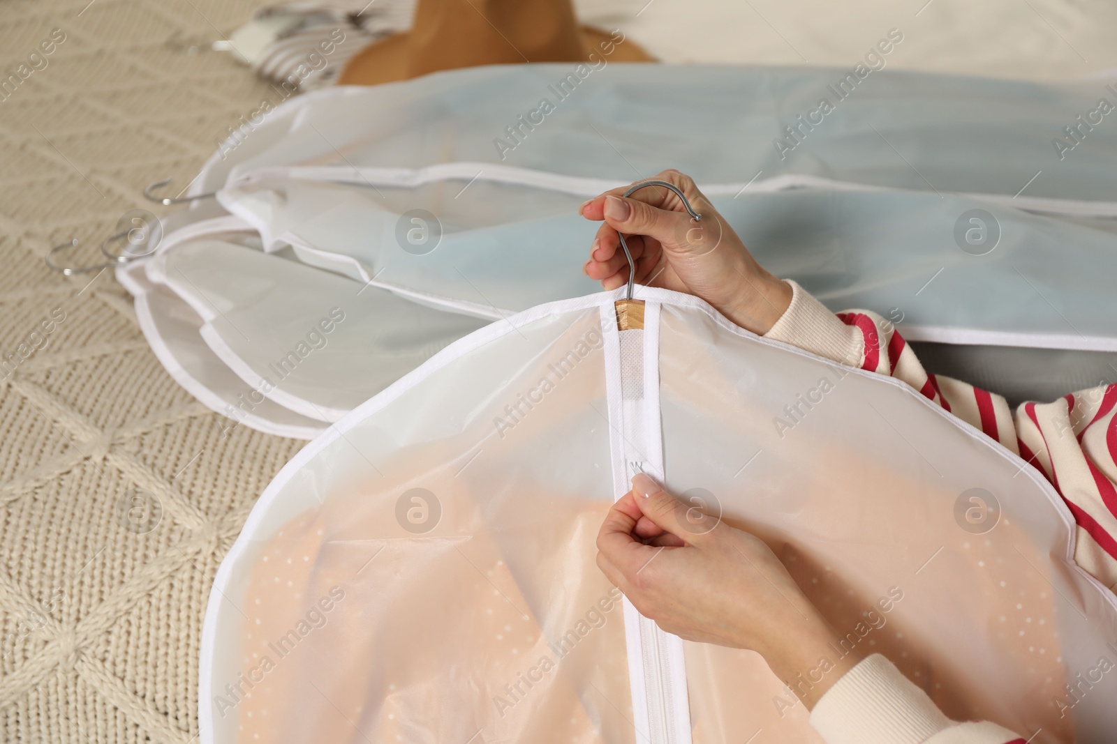 Photo of Woman zipping garment cover with clothes indoors, closeup