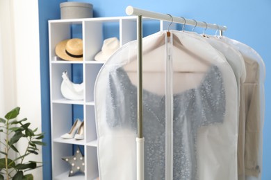 Photo of Garment covers with clothes on rack indoors