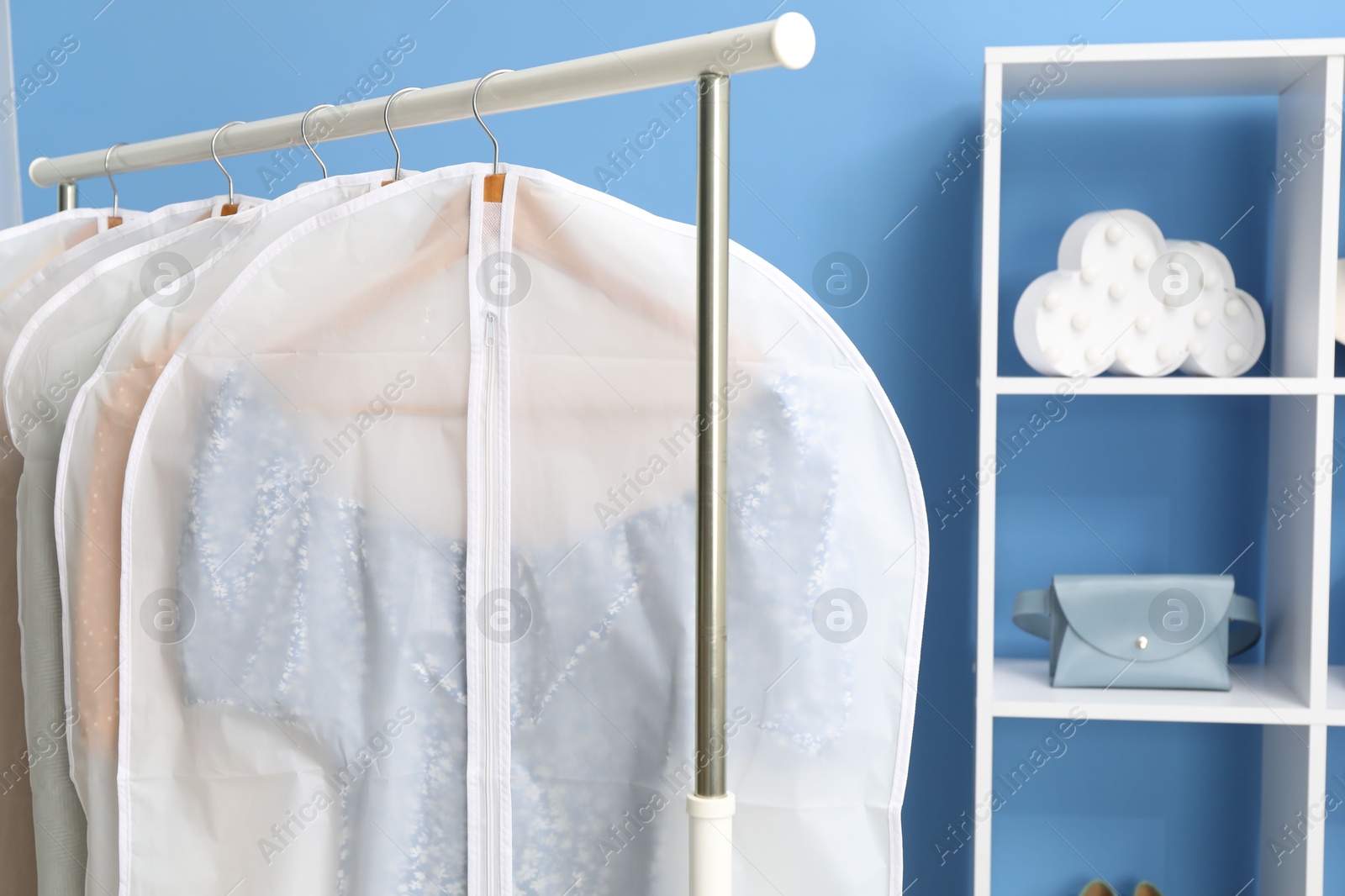 Photo of Garment covers with clothes on rack indoors