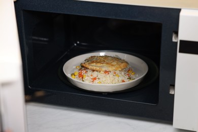 Photo of Plate with rice and meat cutlet in microwave, closeup