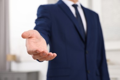 Photo of Offering help. Man reaching his hand indoors, closeup