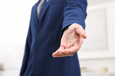 Photo of Offering help. Man reaching his hand indoors, closeup