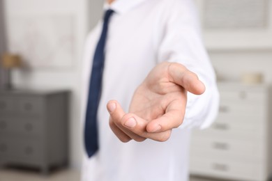 Photo of Offering help. Man reaching his hand indoors, closeup