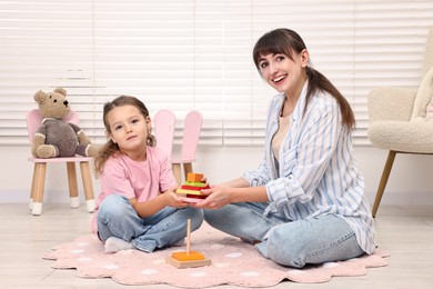 Photo of Autism therapy. Smiling psychologist and little girl playing with educational toy in mental health center