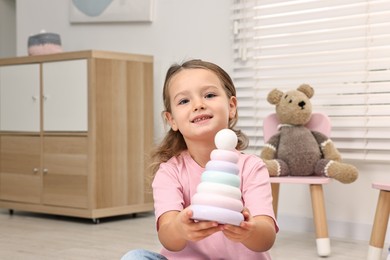 Photo of Autism therapy. Smiling little girl with toy pyramid in mental health center