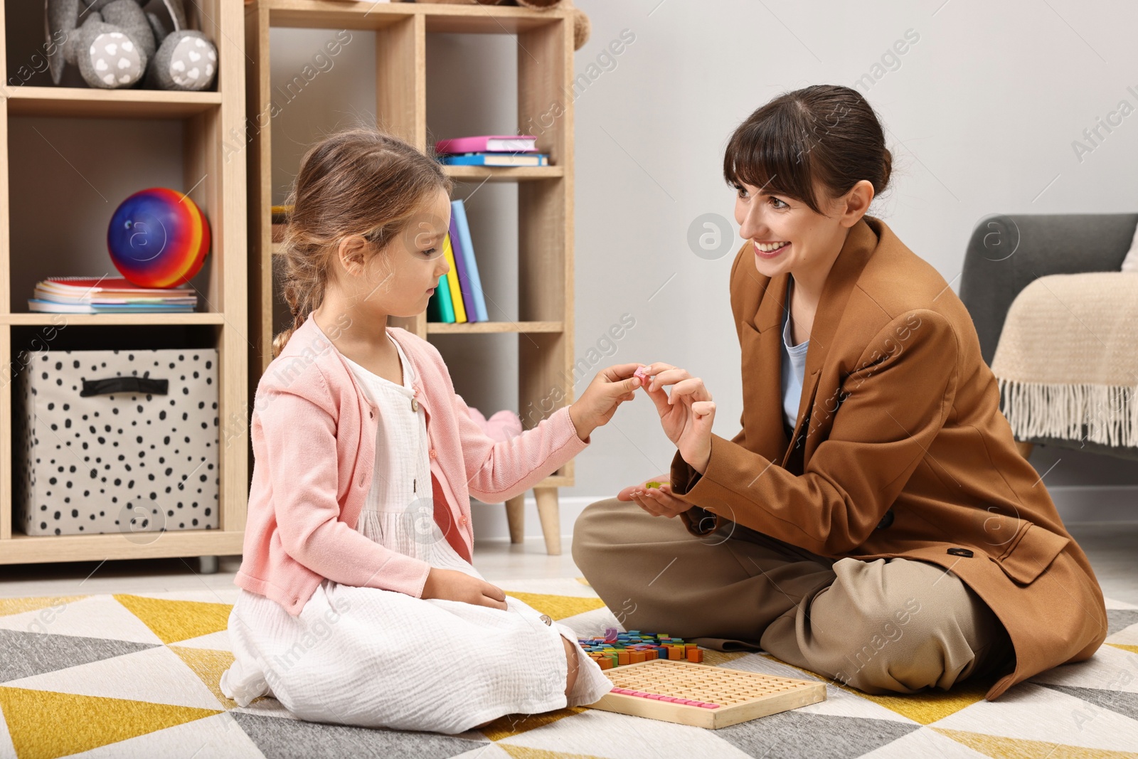 Photo of Autism therapy. Smiling psychologist and little girl playing with educational toy in mental health center