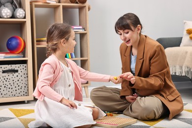 Photo of Autism therapy. Smiling psychologist and little girl playing with educational toy in mental health center