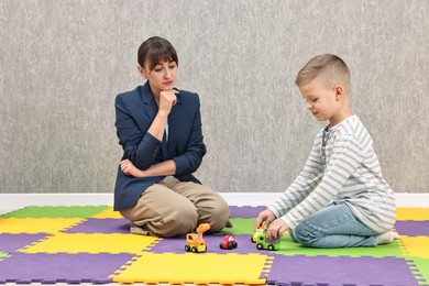 Psychologist observing little boy playing in autism treatment center