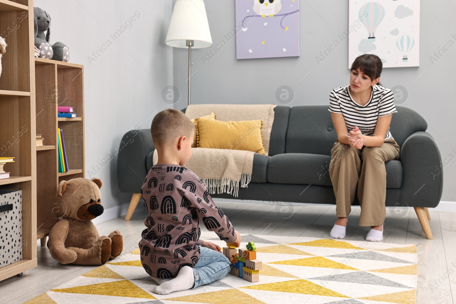 Photo of Psychologist observing little boy playing in autism treatment center