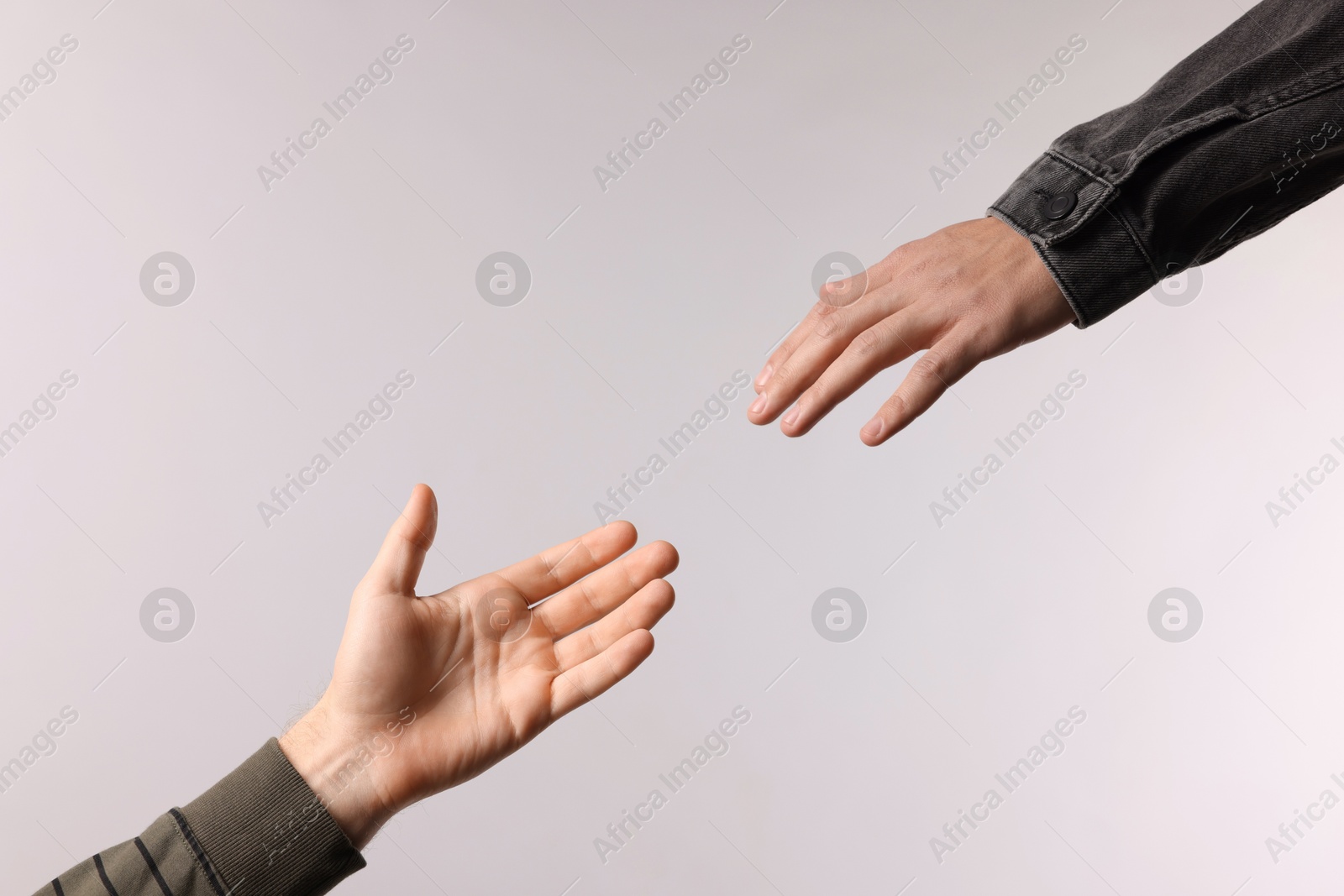 Photo of Man reaching for helping hand on light grey background, closeup