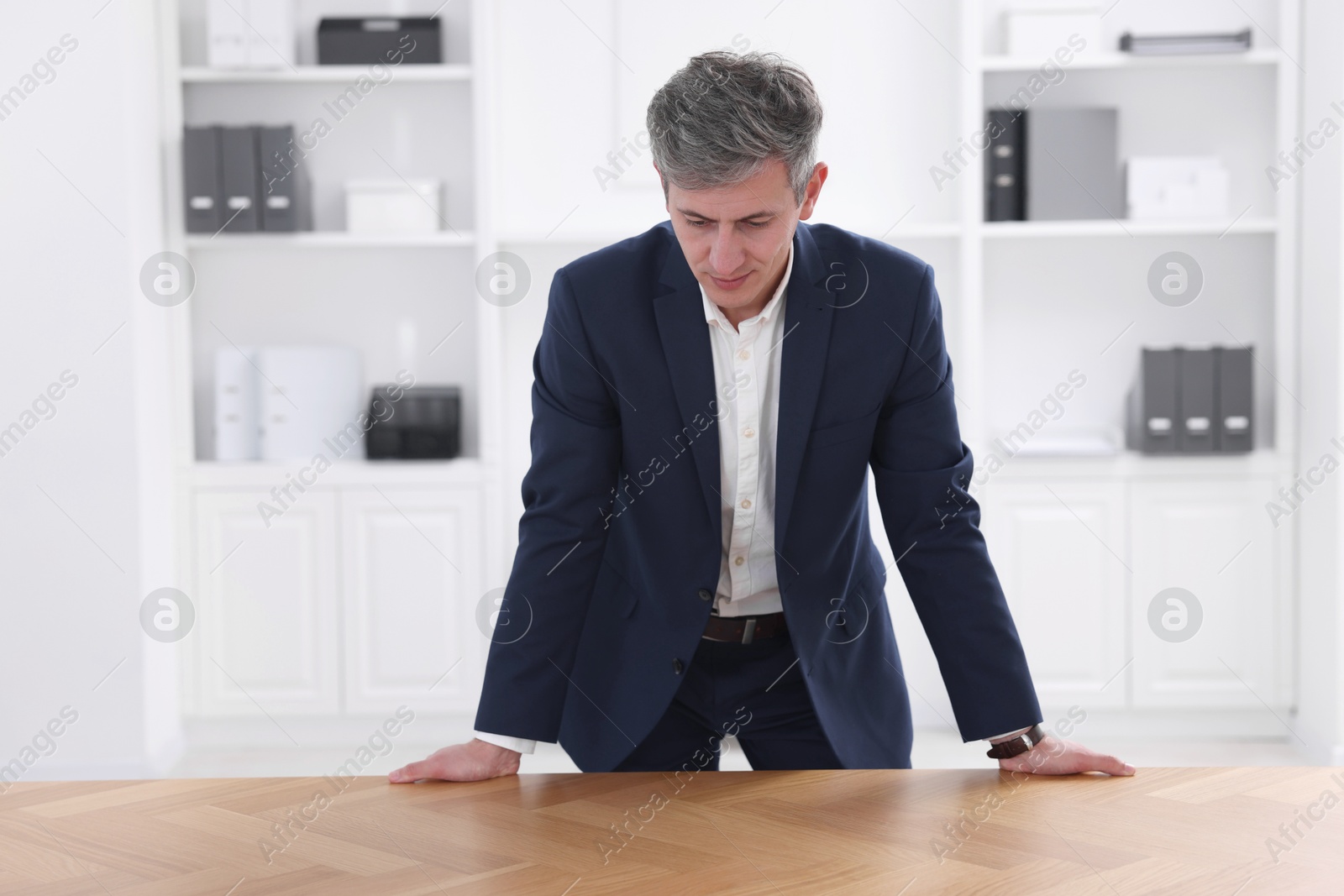 Photo of Man looking at something on desk in office