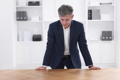 Man looking at something on desk in office