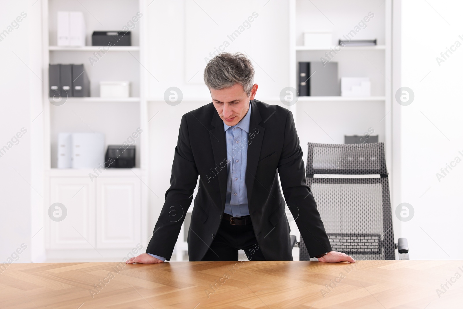 Photo of Man looking at something on desk in office