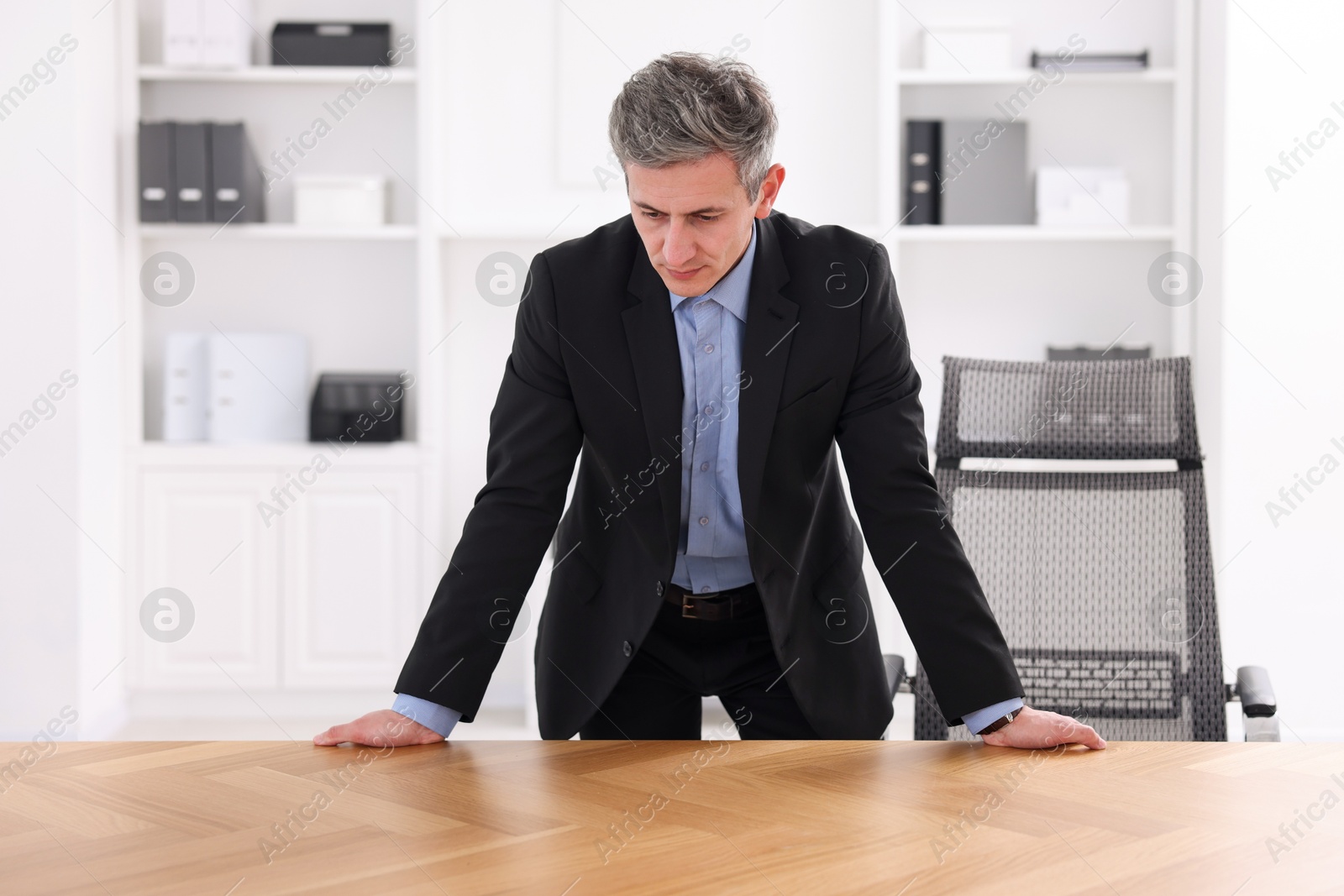 Photo of Man looking at something on desk in office