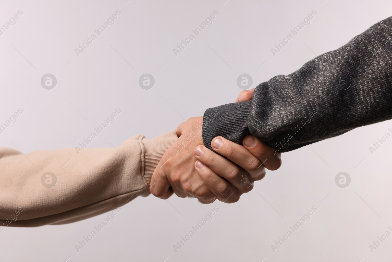 Photo of Help and support. People holding hands on light grey background, closeup