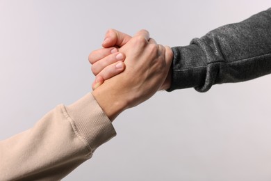 Photo of Help and support. People holding hands on light grey background, closeup