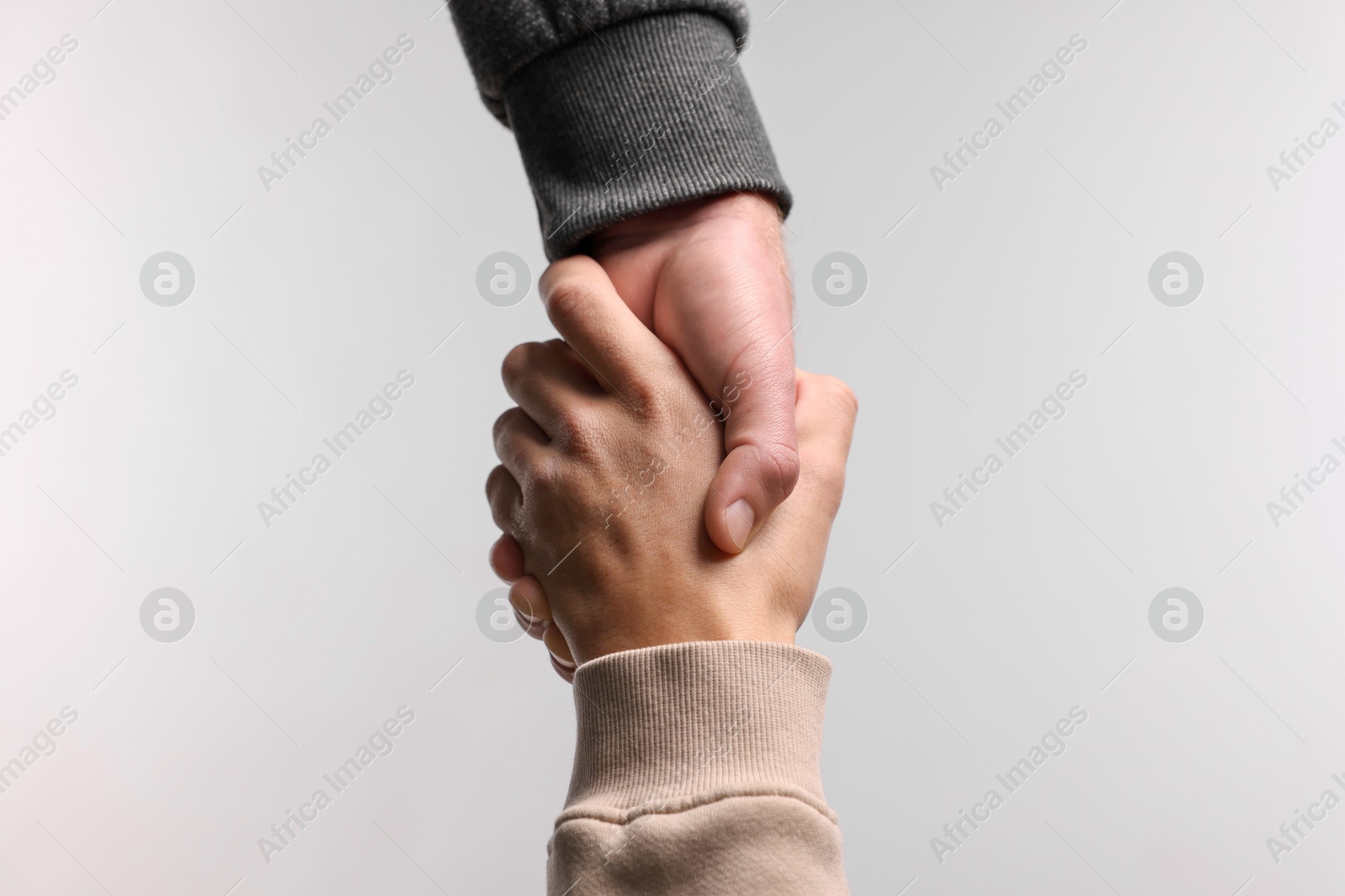 Photo of Help and support. People holding hands on light grey background, closeup