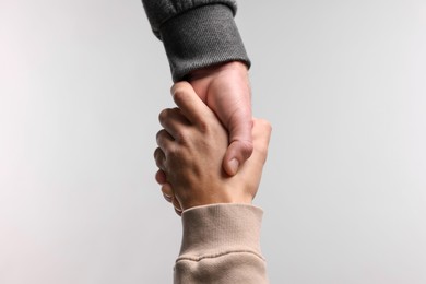 Photo of Help and support. People holding hands on light grey background, closeup