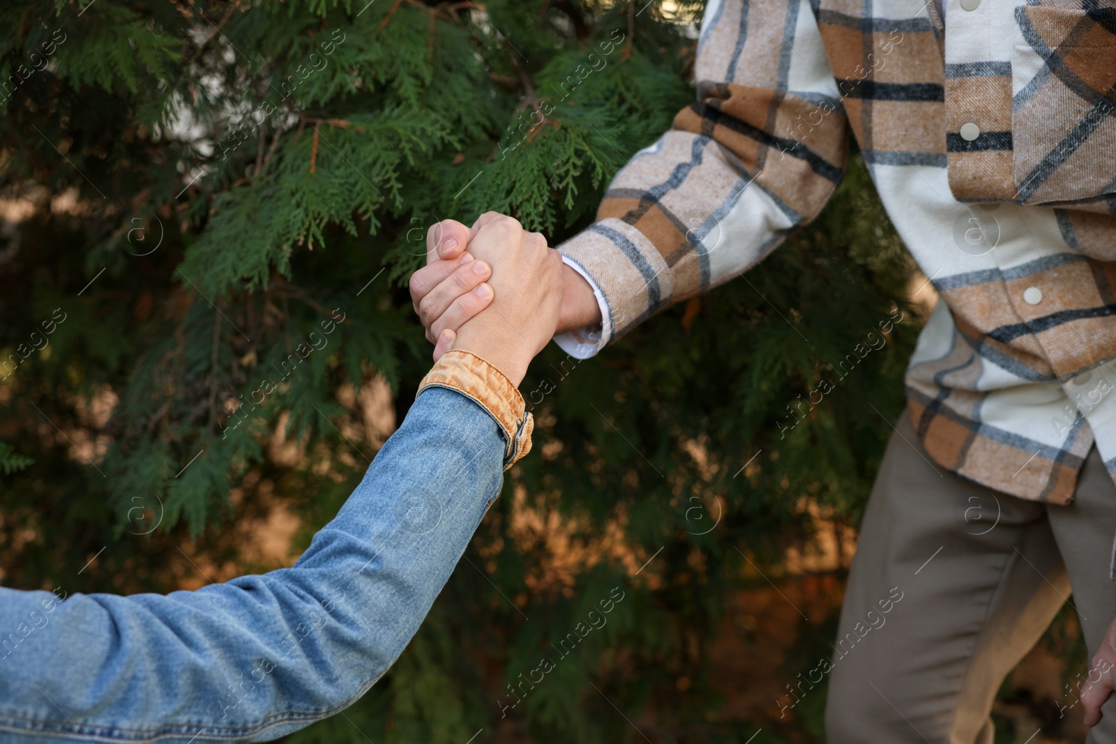 Photo of Help and support. People holding hands outdoors, closeup