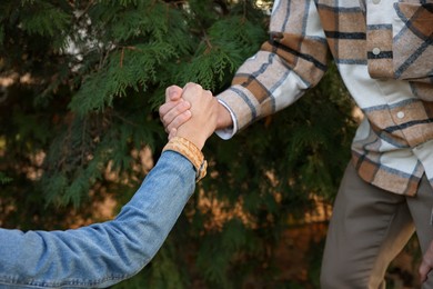 Photo of Help and support. People holding hands outdoors, closeup