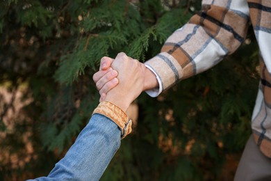 Photo of Help and support. People holding hands outdoors, closeup