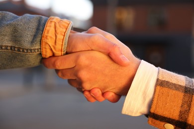 Photo of Help and support. People holding hands on city street, closeup