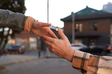 Photo of Man offering helping hand to his friend on city street, closeup