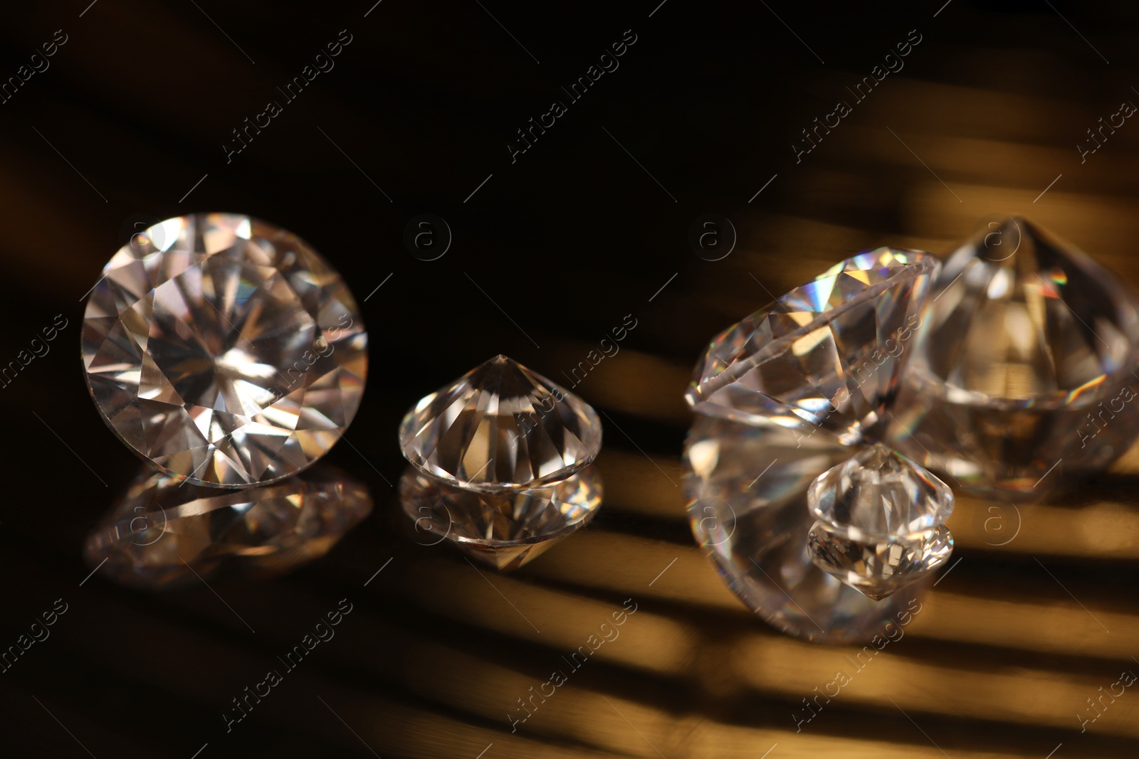 Photo of Beautiful shiny gemstones on golden tray in dark, closeup