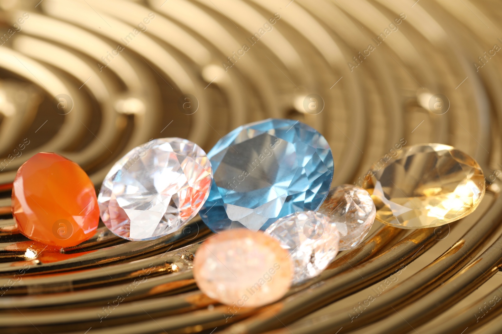 Photo of Beautiful shiny colorful gemstones on golden tray, closeup