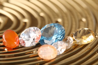 Photo of Beautiful shiny colorful gemstones on golden tray, closeup