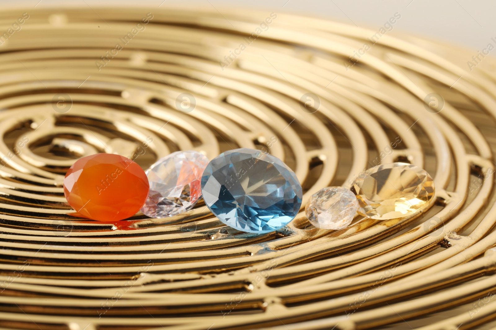 Photo of Beautiful shiny colorful gemstones on golden tray, closeup