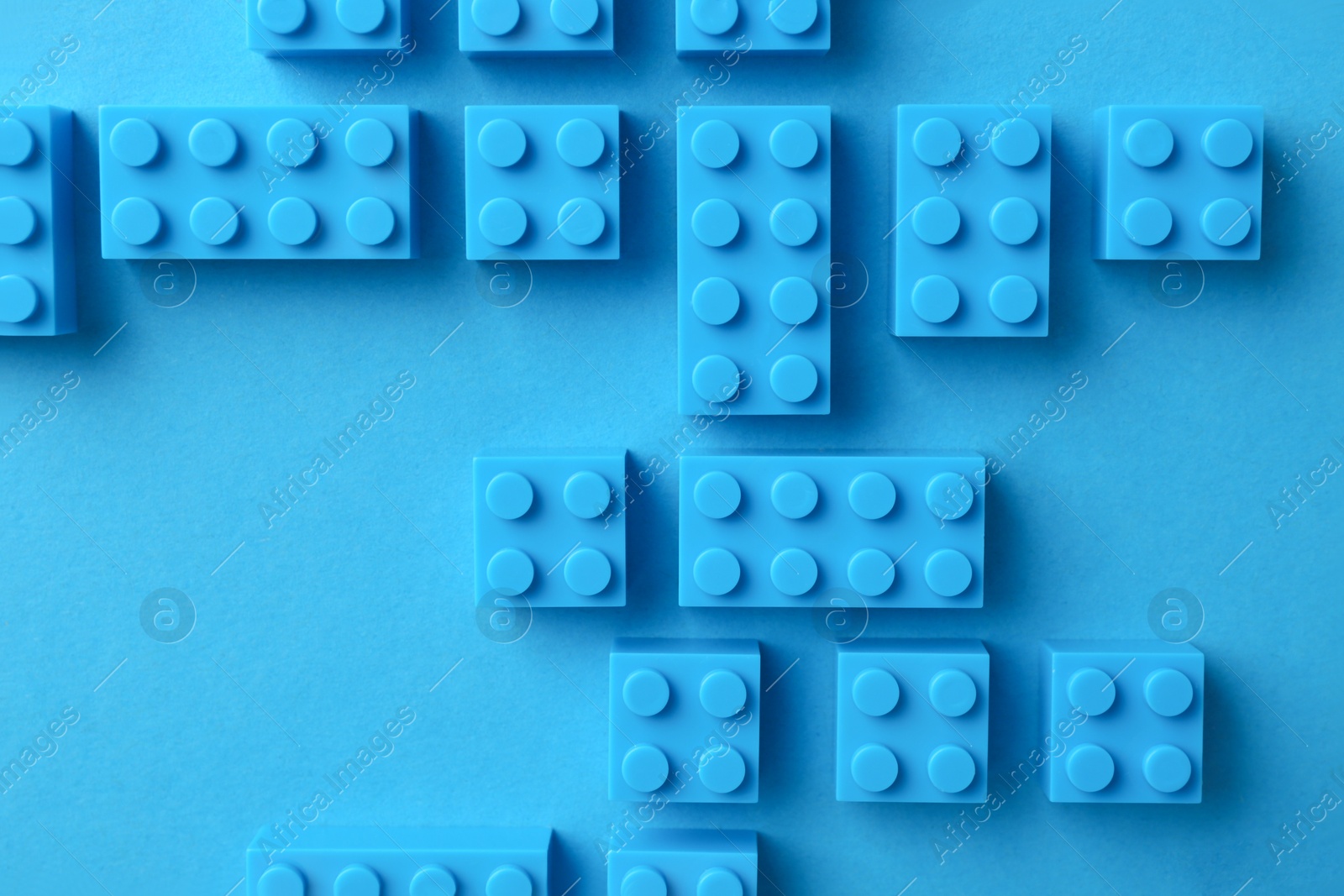 Photo of Constructor toy. Many building blocks on light blue background, flat lay