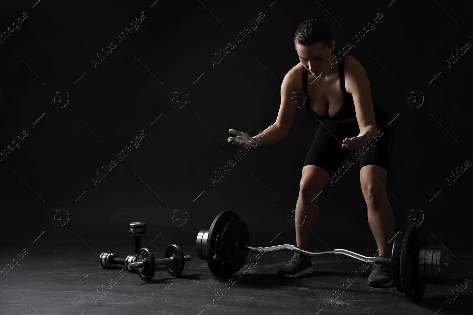 Photo of Woman with talcum powder on her hands preparing to training against black background. Space for text