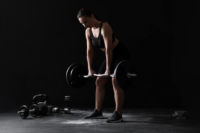 Photo of Woman training with barbell against black background