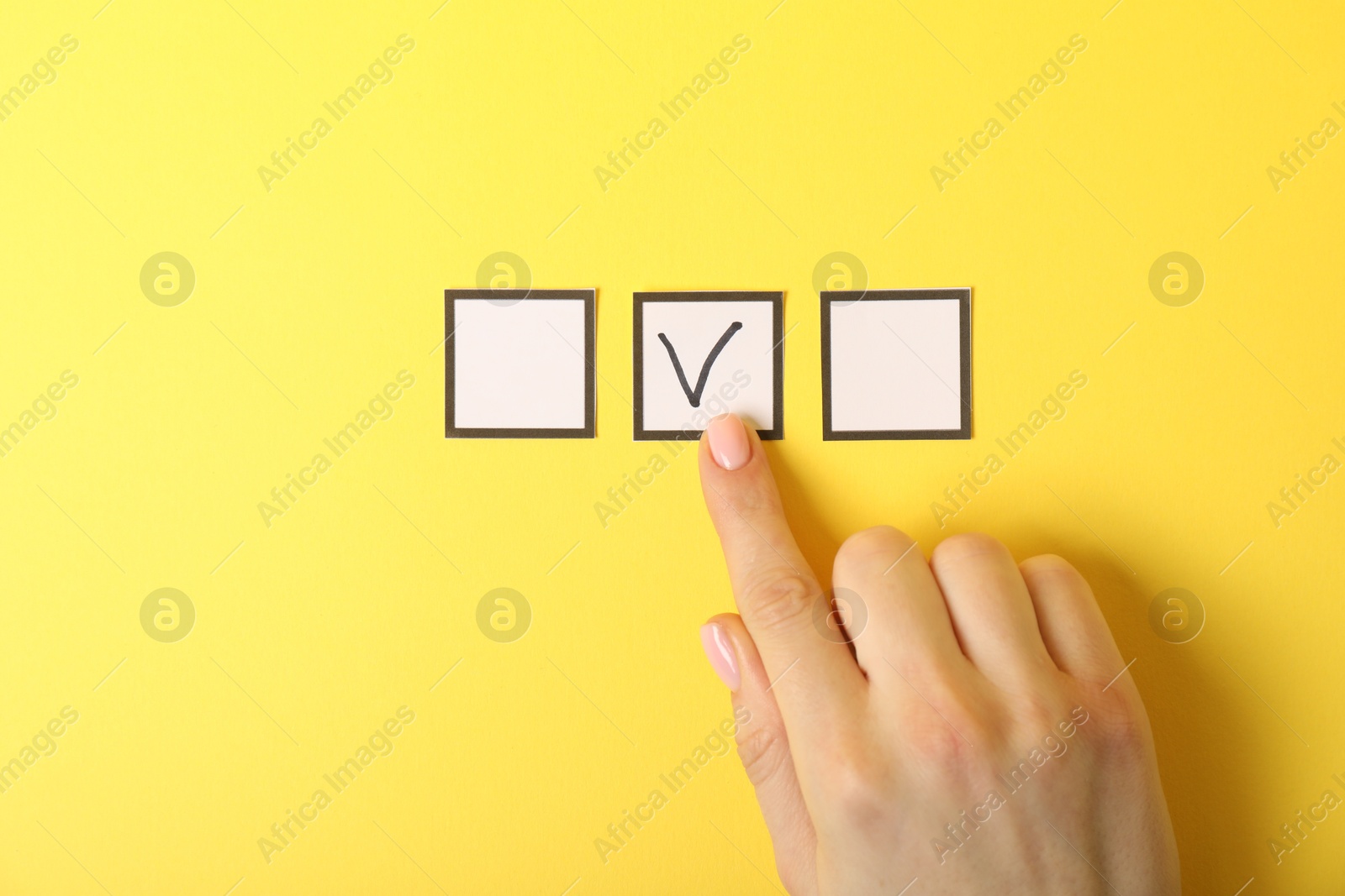 Photo of Woman pointing at checkbox with tick mark on yellow background, top view