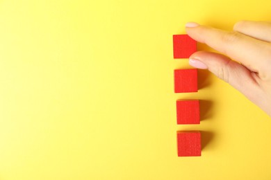 Photo of Woman with red cubes on yellow background, top view. Space for text