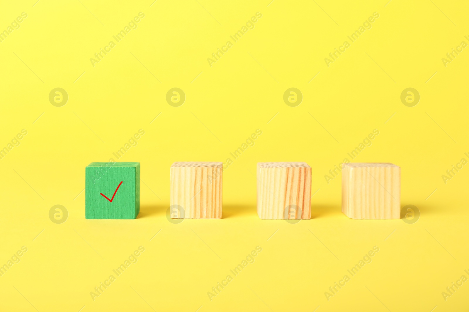 Photo of One green cube with check mark among others on yellow background