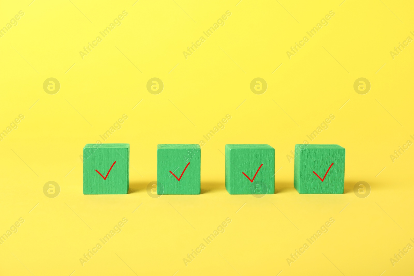 Photo of Green cubes with check marks on yellow background