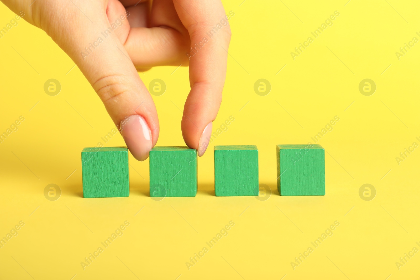 Photo of Woman with green cubes on yellow background, closeup