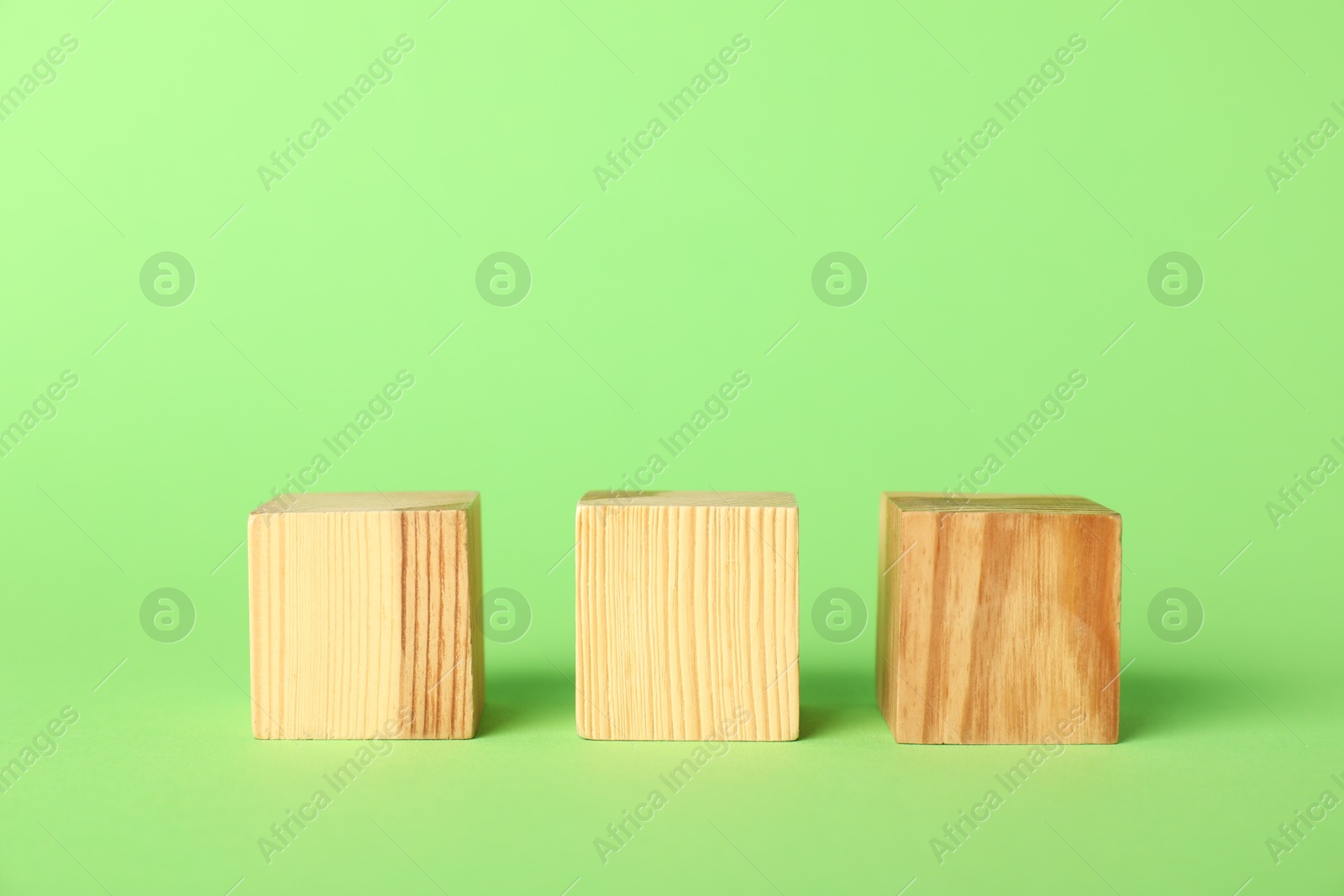 Photo of Wooden cubes on green background, space for text