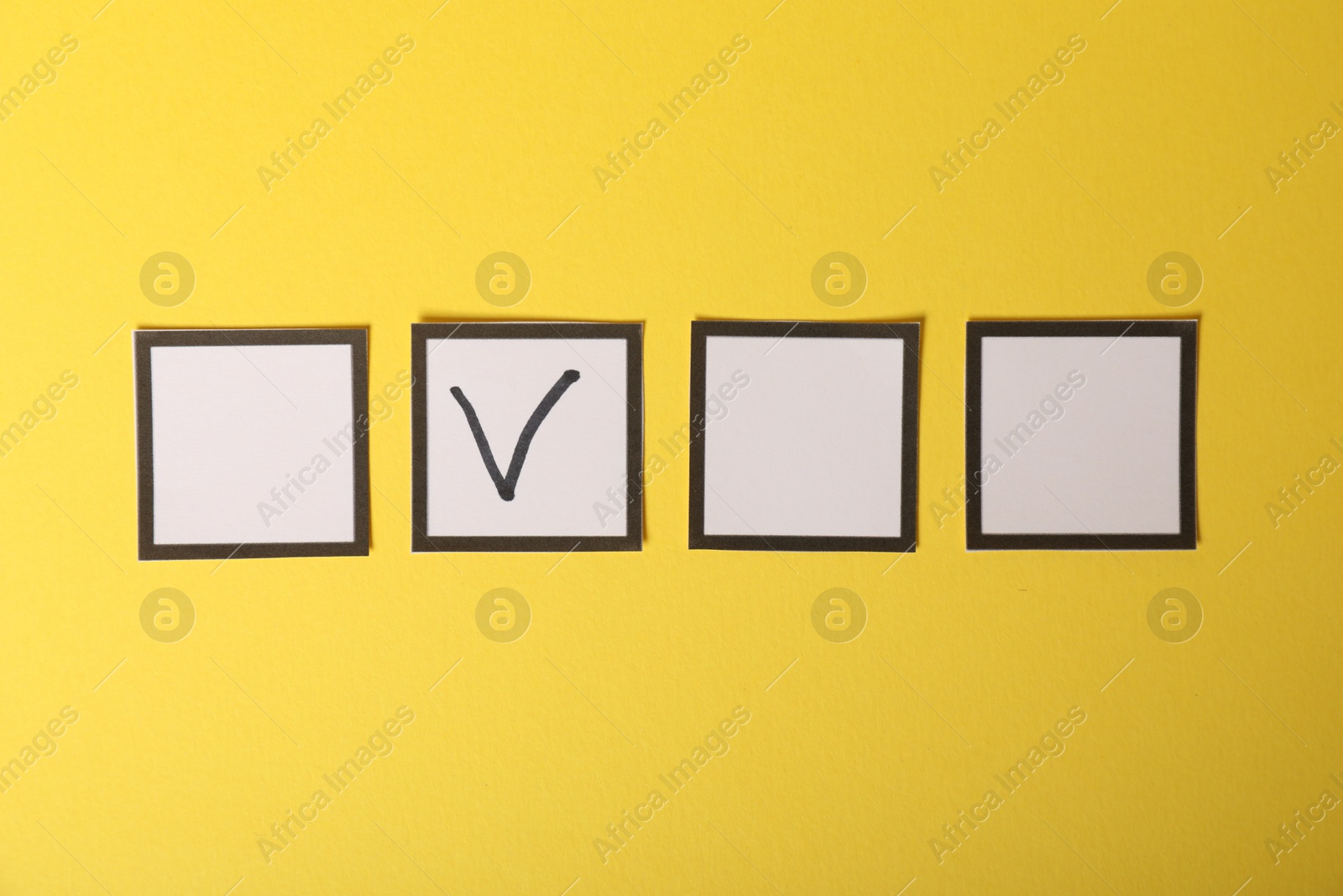 Photo of One checkbox with tick mark among others on yellow background, flat lay