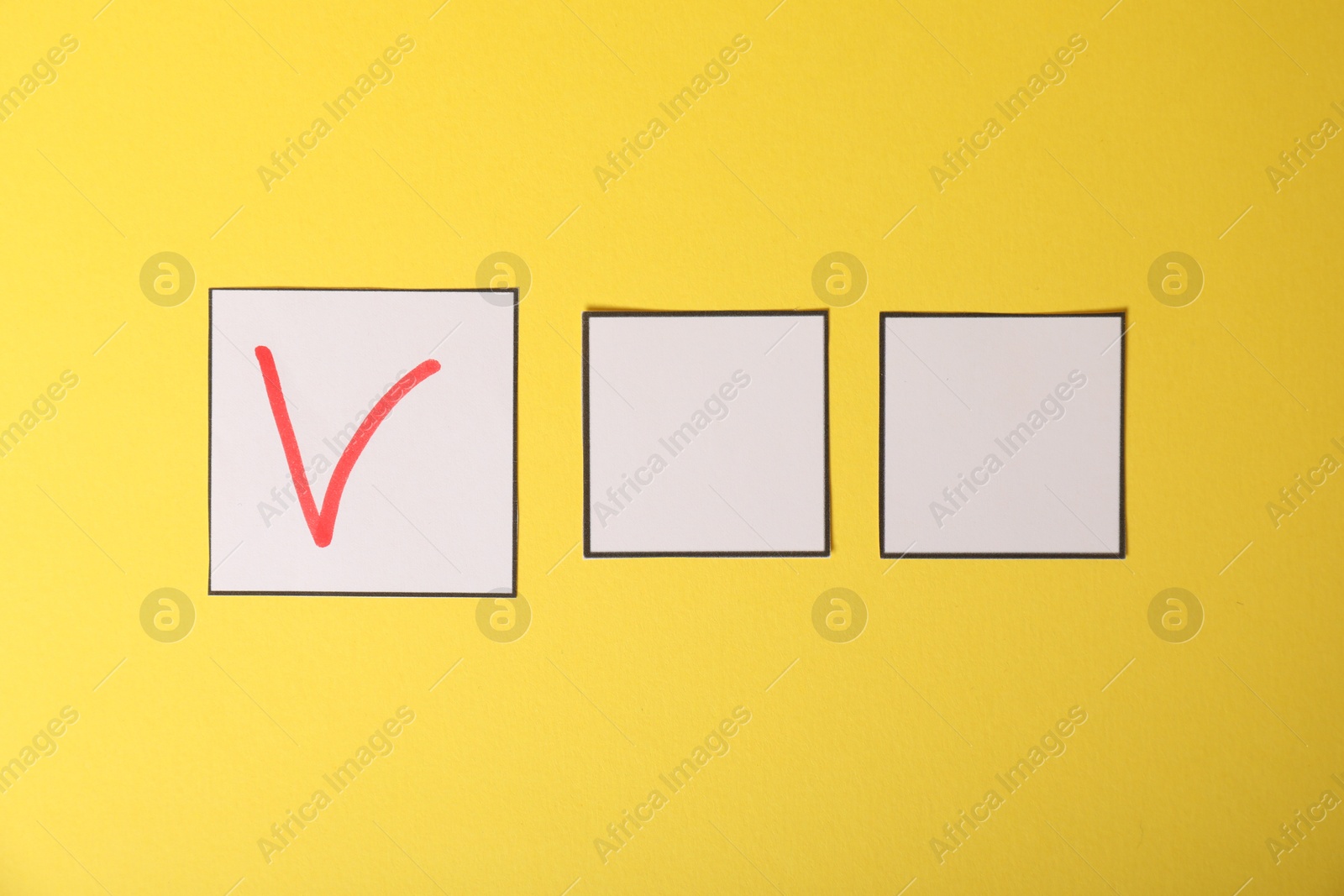 Photo of One checkbox with tick mark among others on yellow background, flat lay