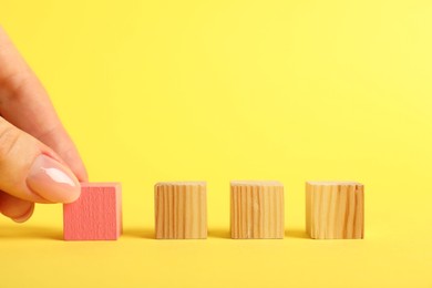 Photo of Woman with wooden cubes on yellow background, closeup