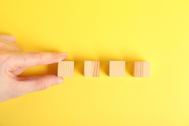 Photo of Woman with wooden cubes on yellow background, top view