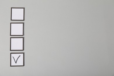 Photo of One checkbox with tick mark among others on grey background, flat lay. Space for text