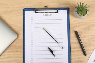 Photo of Checklist with checkboxes, pen, marker, floral decor and laptop on wooden table, flat lay