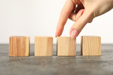 Photo of Woman with wooden cubes at grey table, closeup