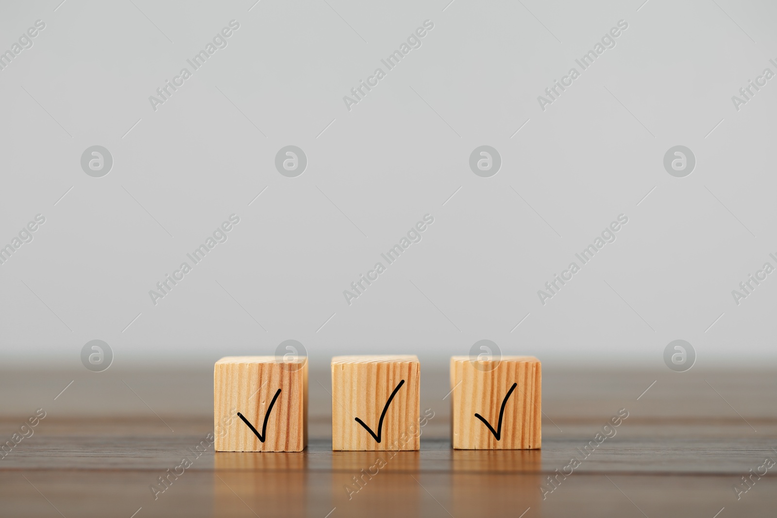 Photo of Wooden cubes with check marks on table, space for text