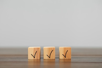 Photo of Wooden cubes with check marks on table, space for text