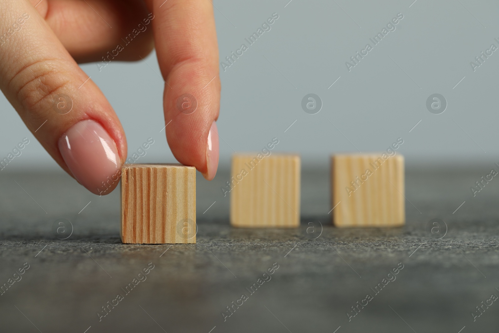 Photo of Woman with wooden cubes at grey table, closeup